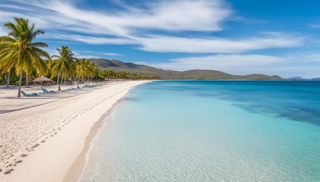 playa ancón Vista panorámica de Playa Ancón en Cuba con arena blanca, palmeras y mar turquesa en un día soleado.